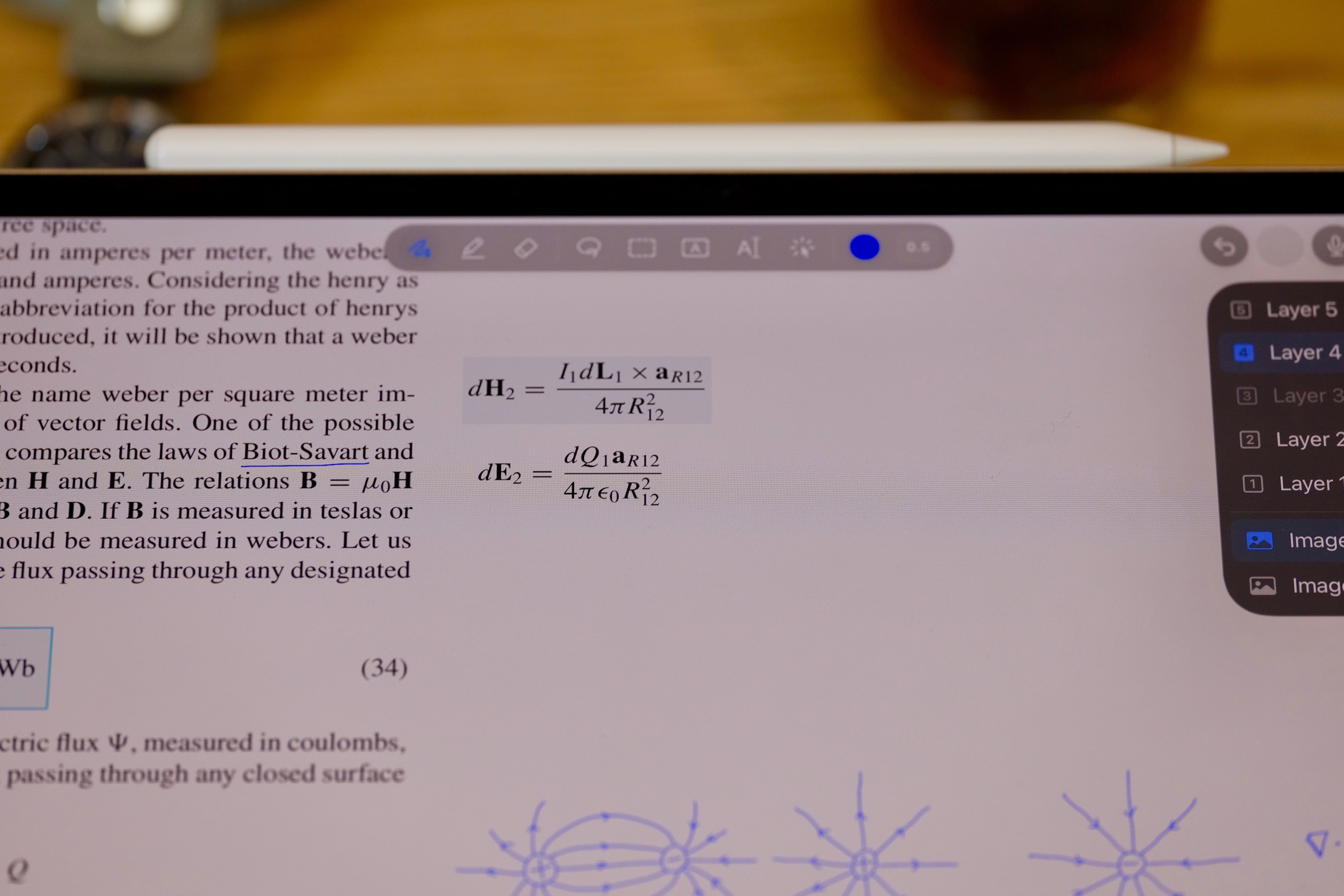 A photographed iPad running UnivNote, with a physics textbook, handwritten diagrams and the layer panel visible.